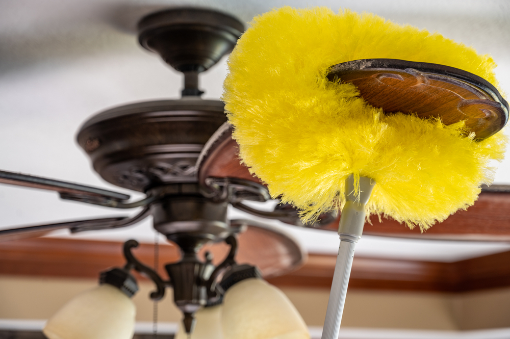 ceiling fan being high dusted with a yellow duster