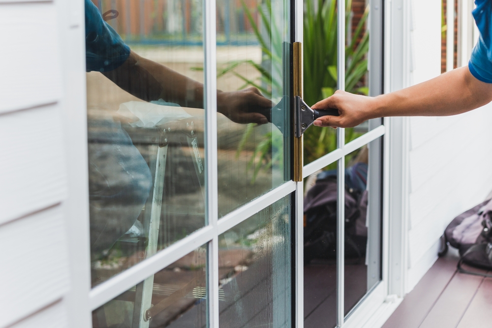 person cleaning a glass door with a squeegee