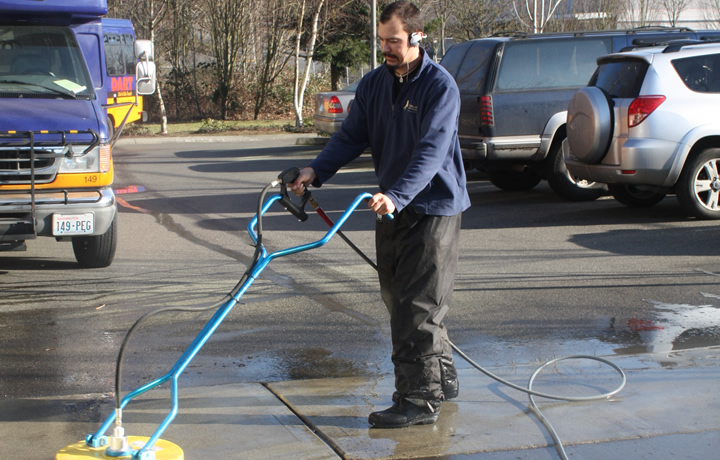 person pressure washing a concrete surface