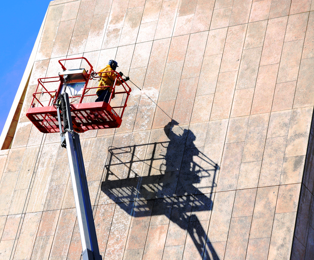 person soft washing side of commercial building